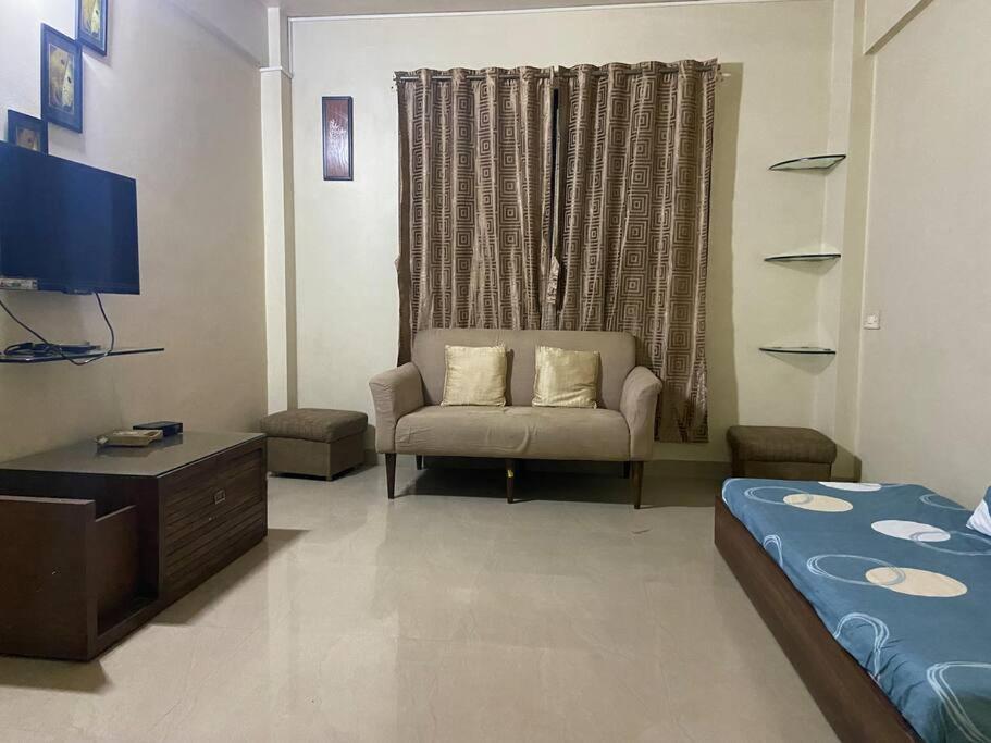 浦那的住宿－Spacious 2 BHK near Commerce Zone，客厅配有床、沙发和电视。