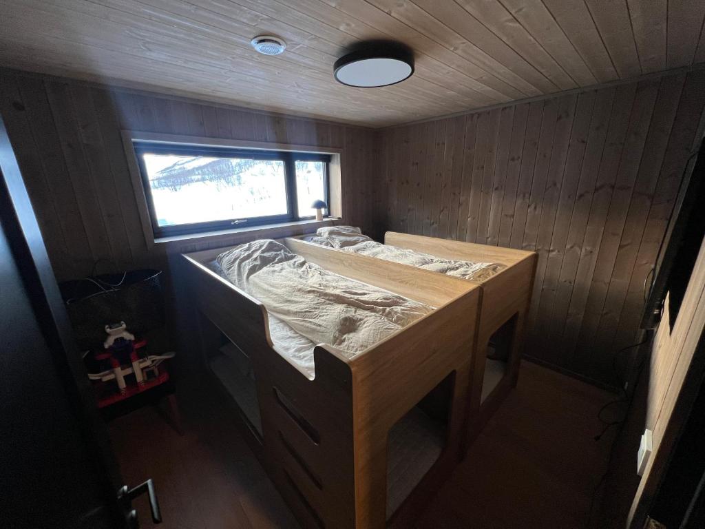 uma cama num pequeno quarto com uma janela em Moderne hytte på Fjellsætra, Ski in/Out, Familievennlig em Sykkylven