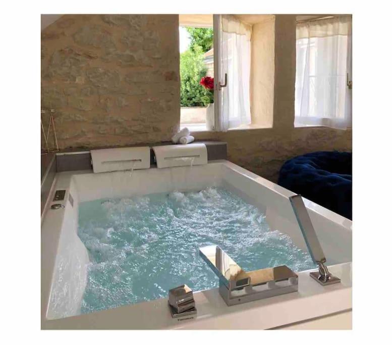 a large bath tub filled with water in a room at Maisonnette spa privée - terrasse commune in Talant
