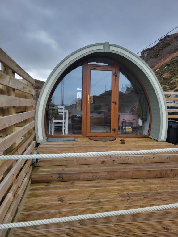 una porta ad arco su una terrazza in legno con finestra di Handa pod in scottish highlands. a Scourie