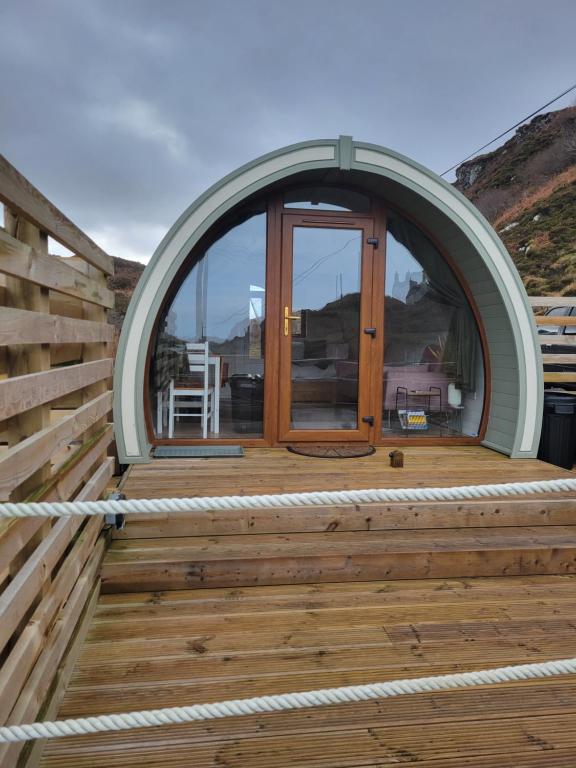 uma porta arqueada num deque de madeira com uma janela em Handa pod in scottish highlands. em Scourie