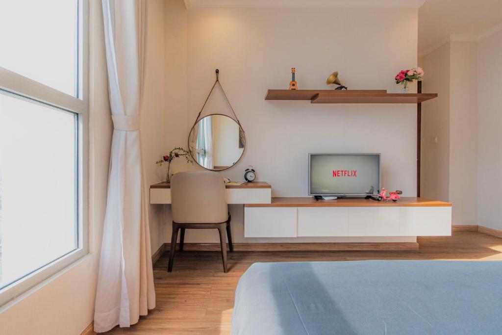 a room with a desk with a tv and a mirror at Raddison Luxury Apart - Vinhome Central Park, Landmark 81 Area and Great Park in Ho Chi Minh City