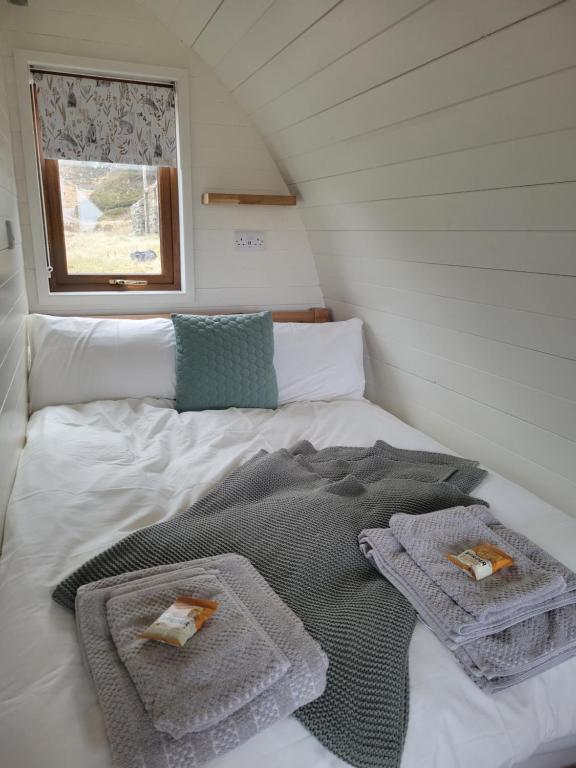 un letto con asciugamani sopra in una piccola stanza di Handa pod in scottish highlands. a Scourie