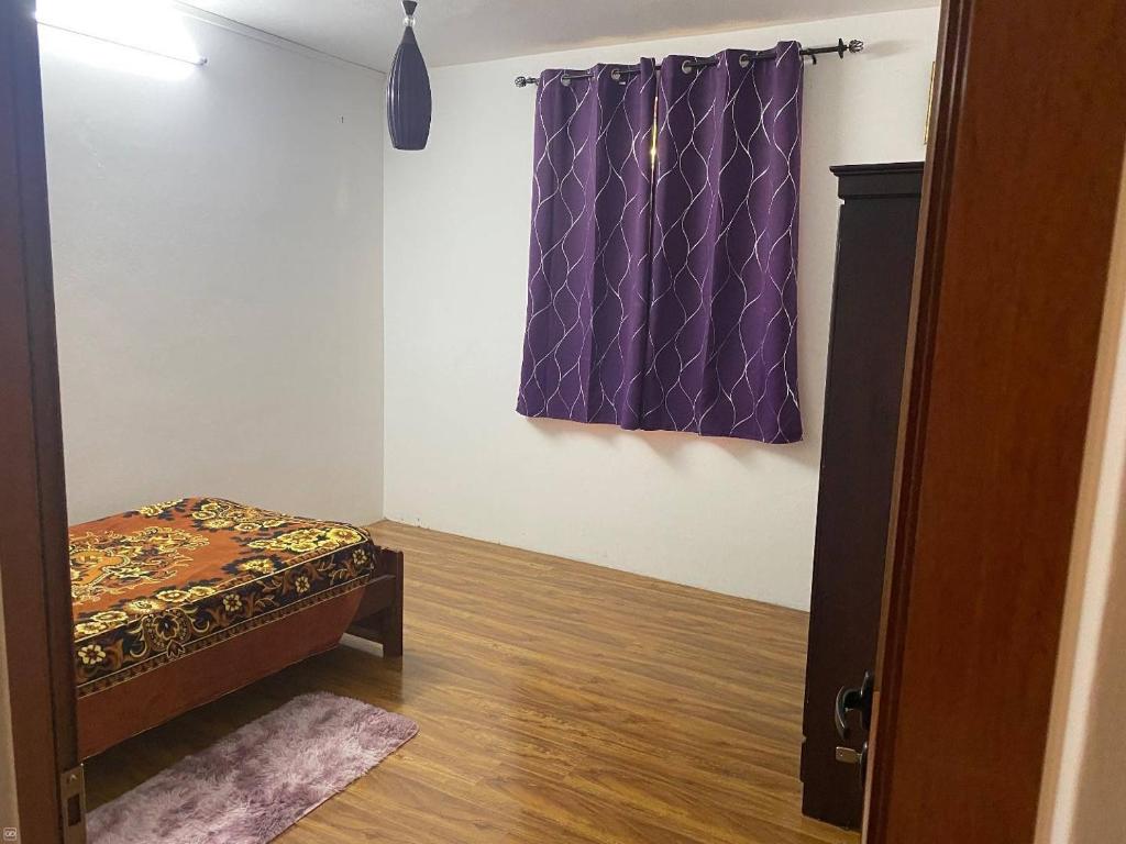 カトル・ボルヌにあるMountain Tranquilityのベッドルーム1室(ベッド1台付)、紫色のカーテン付きの窓が備わります。