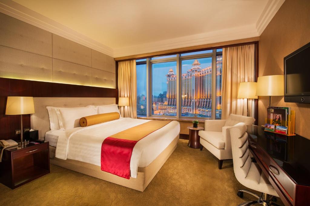 een slaapkamer met een groot bed en een groot raam bij Broadway Hotel in Macau
