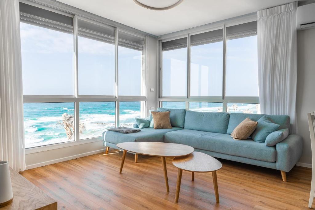 a living room with a blue couch and a table at O&O Group - Amazing Seaview 3 BR Apartment in Bat Yam