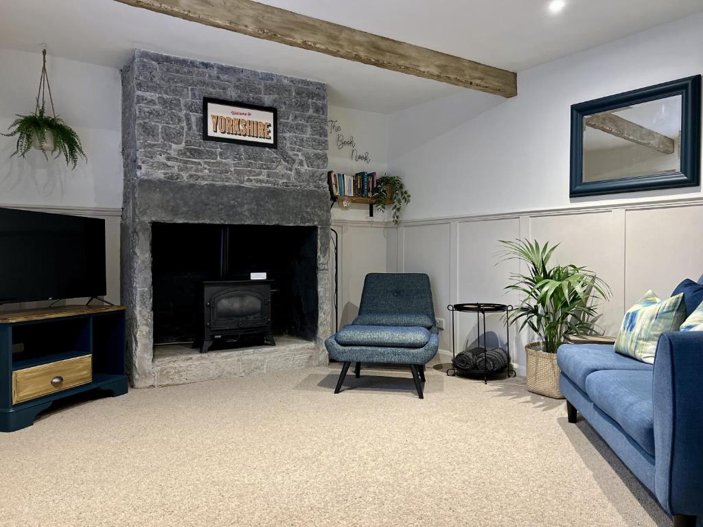 a living room with a fireplace and a blue chair at Nine Cooper Lane, Holmfirth in Holmfirth