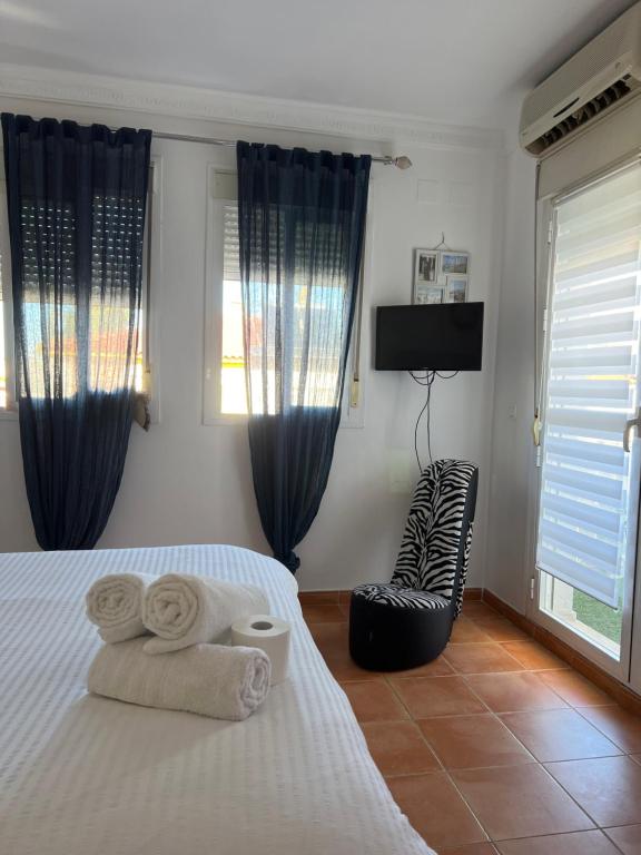 1 dormitorio con 1 cama con toallas y silla en Circus-Goretti House, en Mairena del Aljarafe