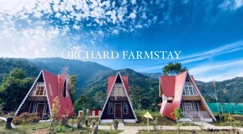 a group of houses with mountains in the background at Orchard Farmstay in Bijanbāri Bāzār
