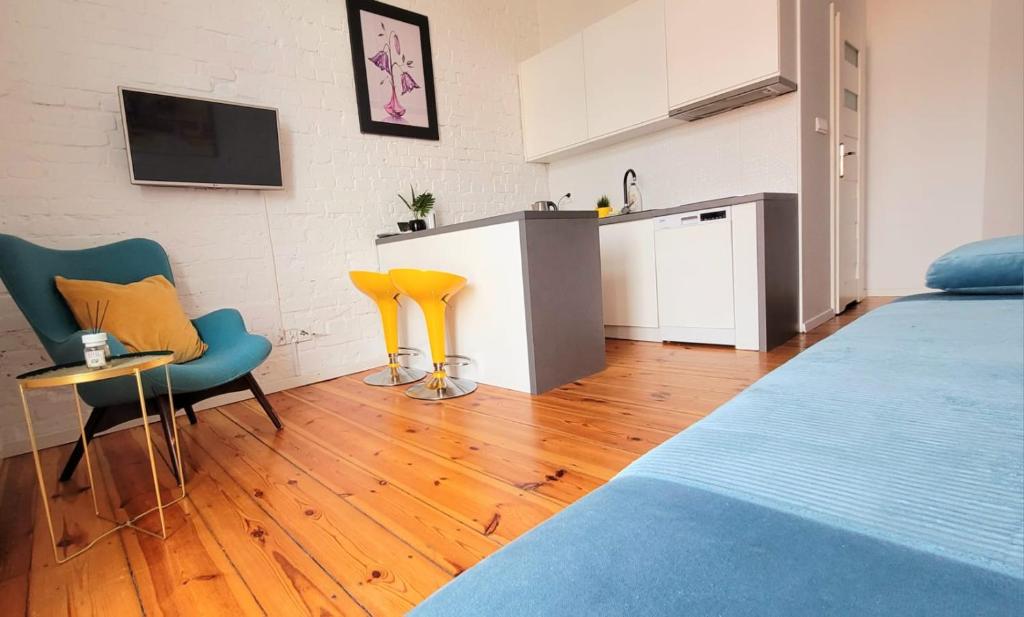 une chambre avec un lit et une cuisine avec des chaises jaunes dans l'établissement apartament w centrum miasta, à Bydgoszcz