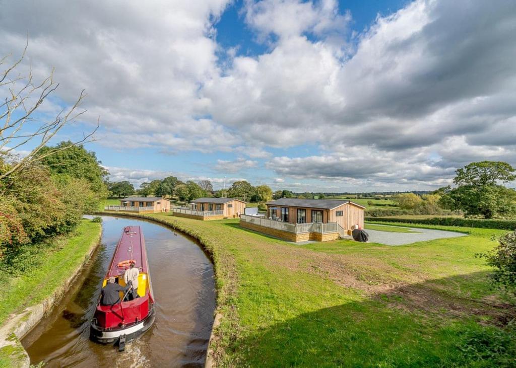 a small boat on a canal with houses in the background at Winston Farm Lodges 