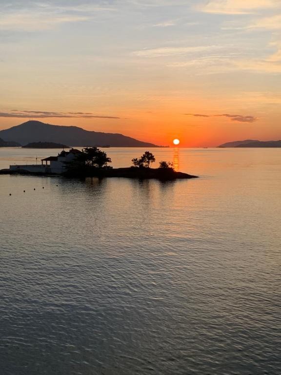 a small island in the water at sunset at Apartamento Praia do Bonfim in Angra dos Reis