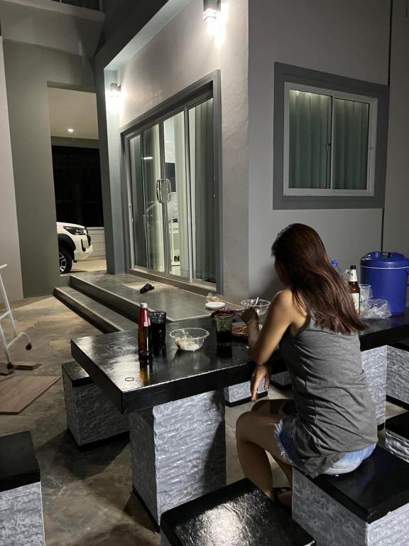 una donna seduta a un tavolo in una stanza di บ้านเดี่ยว 4 ห้องนอน 3 ห้องน้ำ a Ban Noi Pho Kham