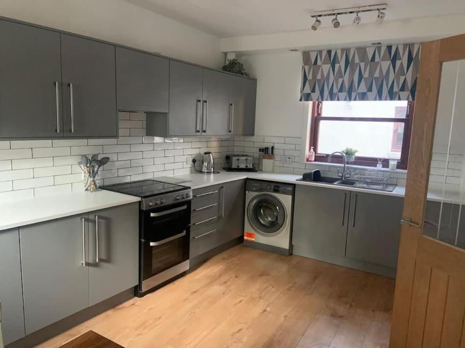 a kitchen with gray cabinets and a washer and dryer at Central 3 Bedroom Townhouse in Wick