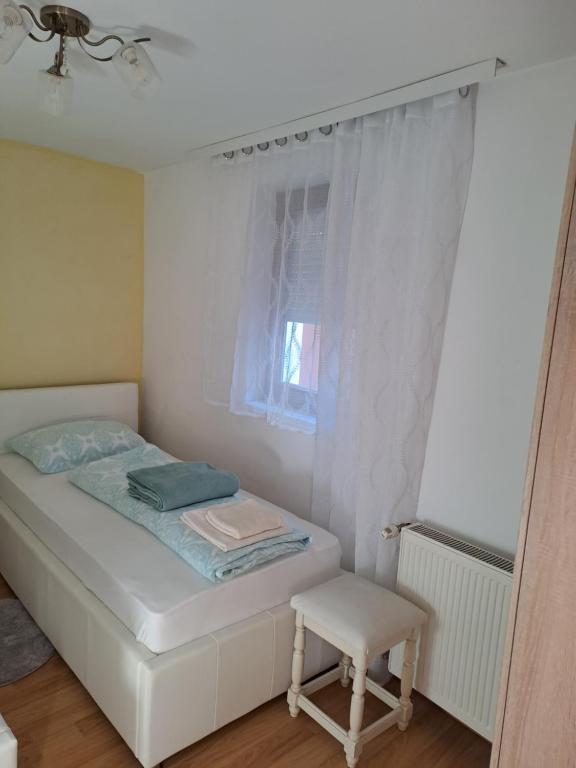 a small bedroom with a bed and a chair at Lavanda in Vukovar