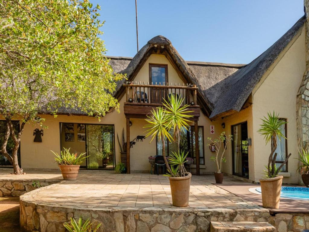 a house with a thatched roof and a swimming pool at Impala Cottage in Hoedspruit