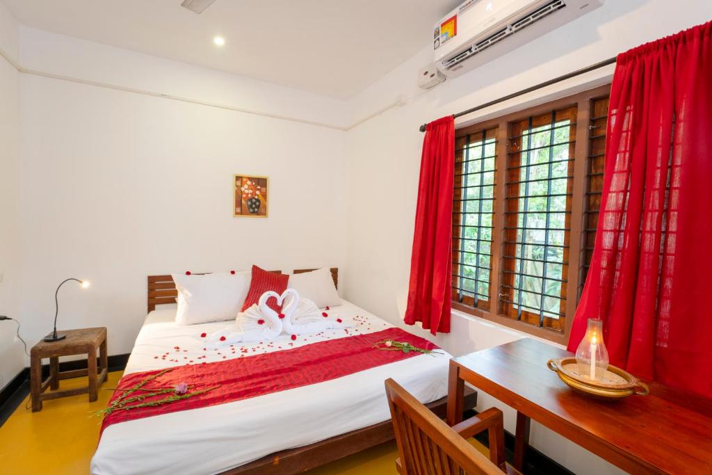 - une chambre avec un lit, un bureau et des rideaux rouges dans l'établissement Ananda Marari Heritage Villa, à Alappuzha