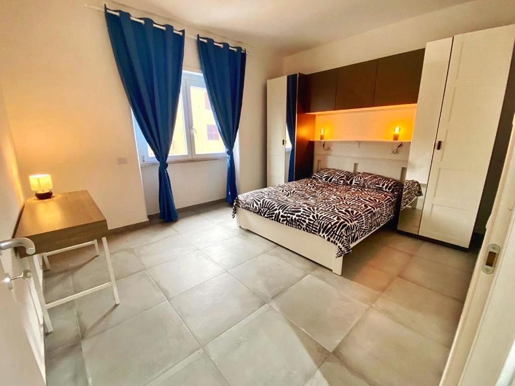 um quarto com uma cama, uma mesa e cortinas azuis em Moderno Appartamento - Anzio em Anzio