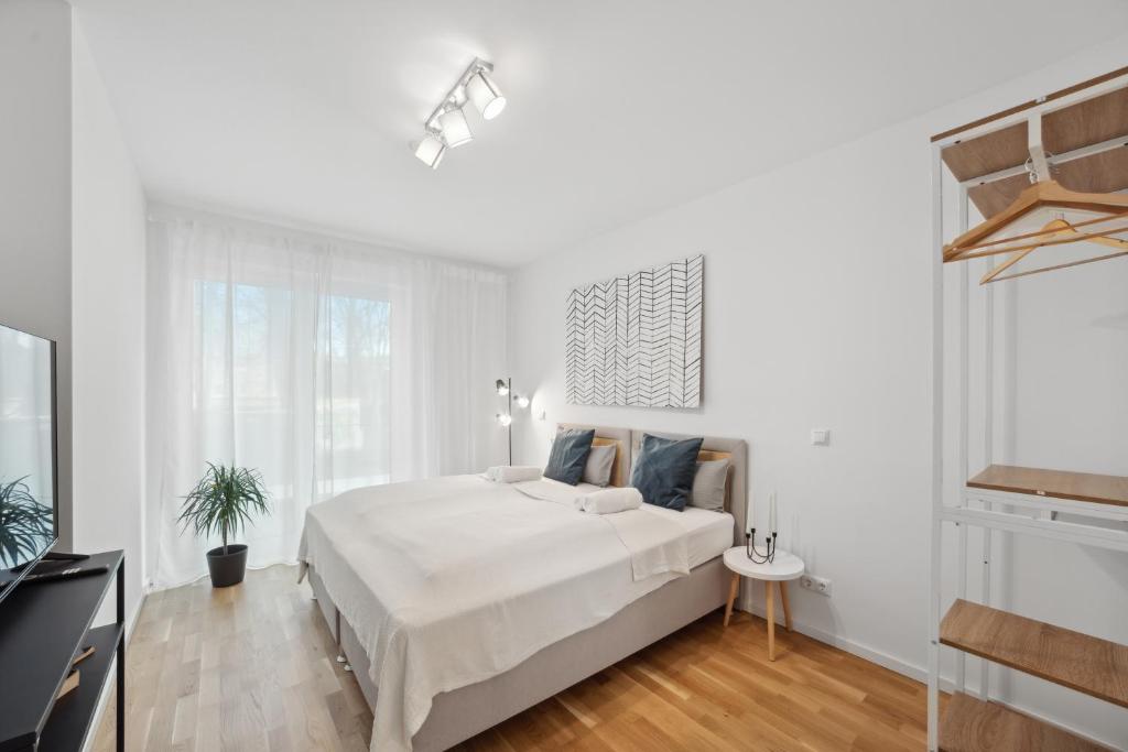 a white bedroom with a large bed and a window at Sali Homes/ R1 Gemütliches Apartment am Fluss in Bayreuth