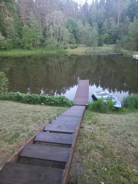 a wooden walkway over a lake with a boat at Gliemji in Krāslava