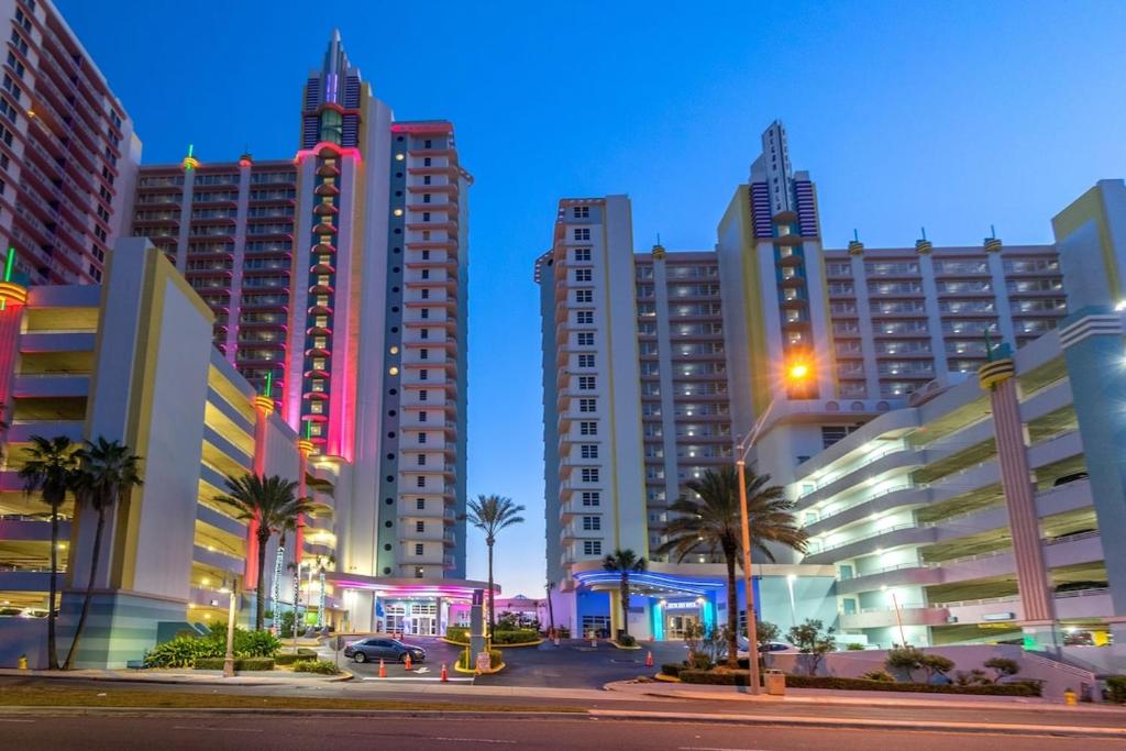 a city at night with tall buildings and palm trees at 2 BR Resort Condo Direct Oceanfront Wyndham Ocean Walk - Daytona Funland 1601 in Daytona Beach