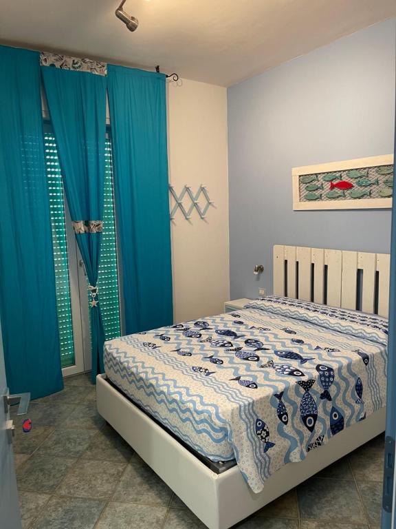a bedroom with a bed and blue curtains at Sunrise B&B Le castella in Le Castella