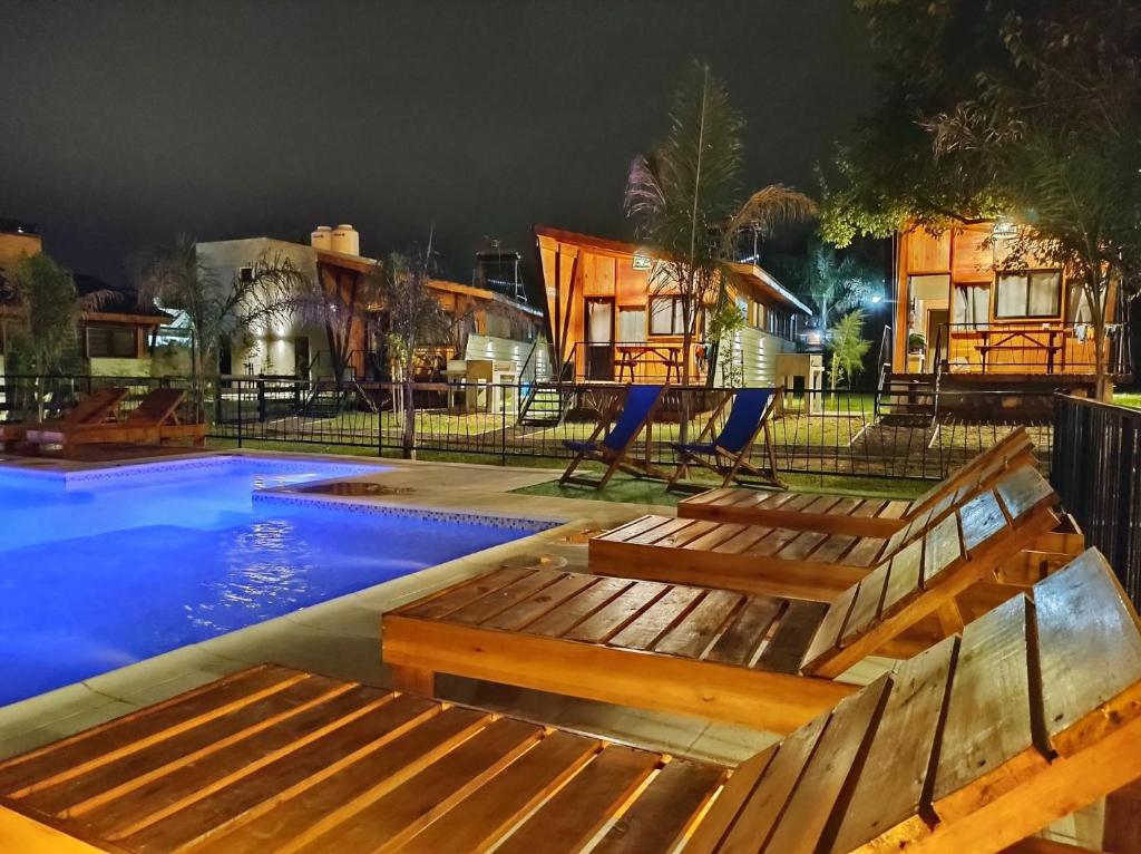 - une piscine avec un banc en bois à côté d'une aire de jeux dans l'établissement Cabañas Posta Litoral, à Colón
