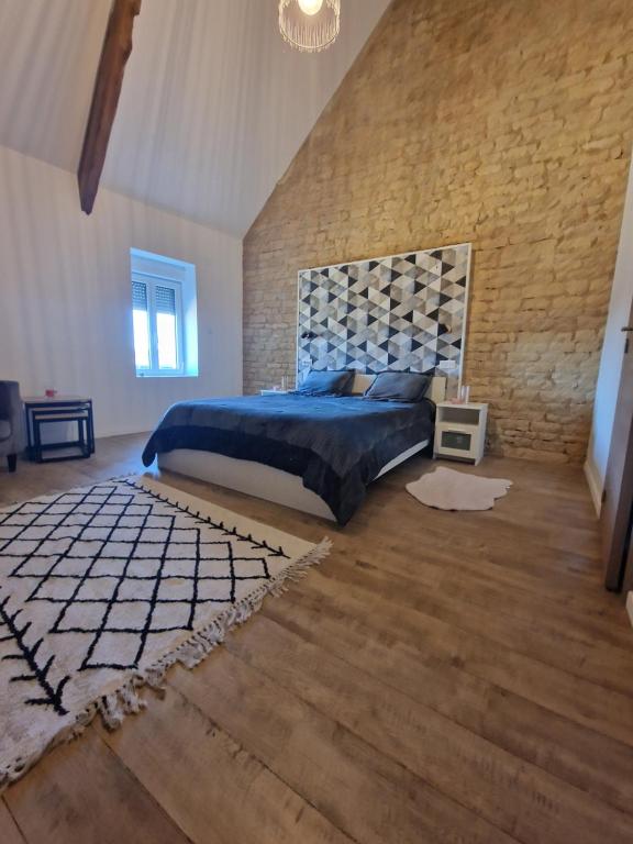 sypialnia z dużym łóżkiem i ceglaną ścianą w obiekcie Maison tres agrable 5 min de courseulles sur mer 