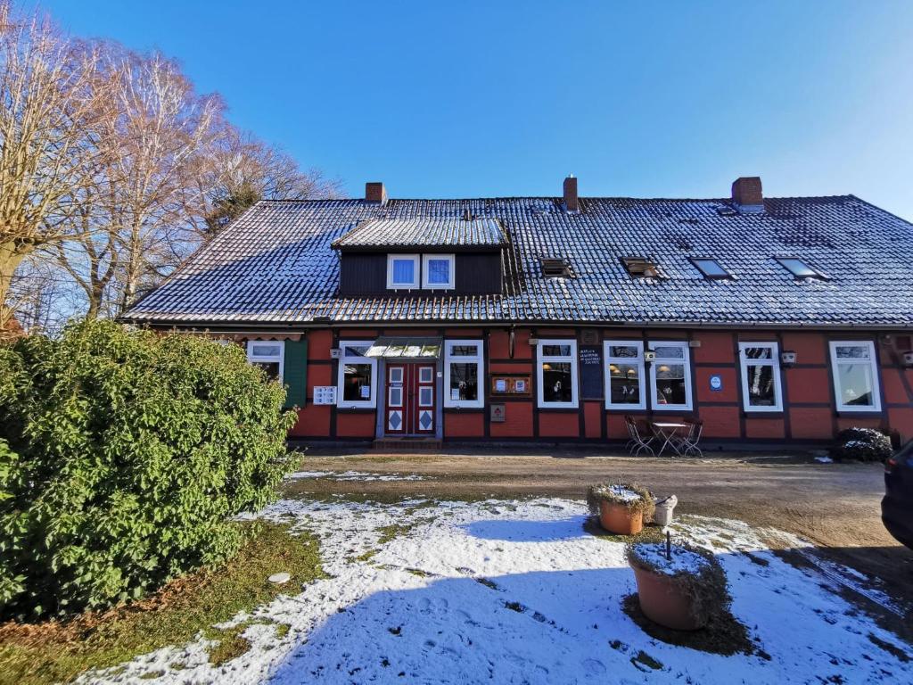 a red house with a roof with snow on the ground at Gasthaus Zur Riete in Celle