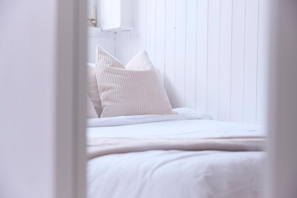 uma cama com lençóis brancos e almofadas ao lado de uma janela em Apartment in Angel. em Londres