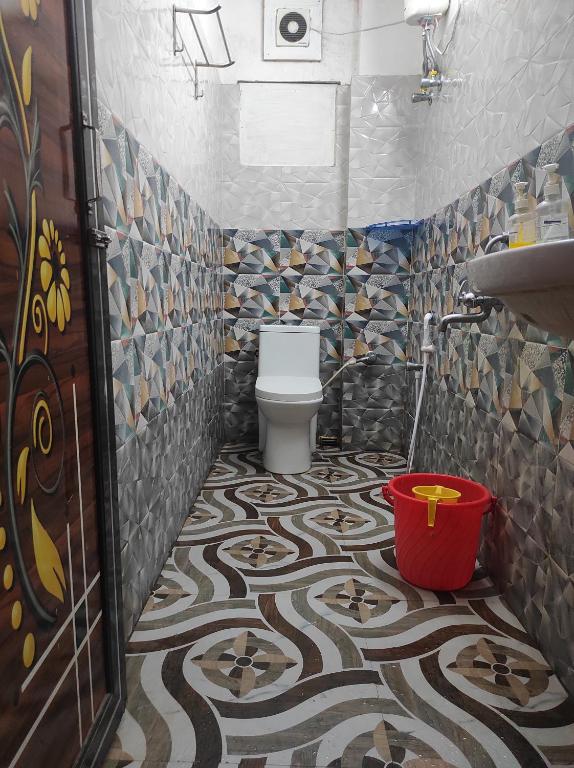 a bathroom with a toilet and a mosaic tile floor at Star VIP-Inn Kolkata Airport in Kolkata