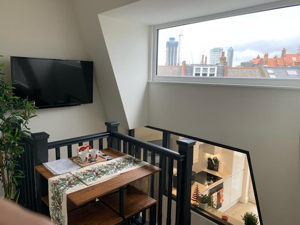 a balcony with a table and a tv and a window at One Bedroom Apartment London in London