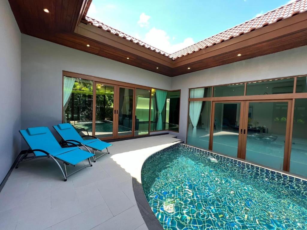 um pátio com uma piscina e 2 cadeiras azuis em Ocean Palms Luxury Villa Bangtao Beach Phuket em Praia de Bang Tao