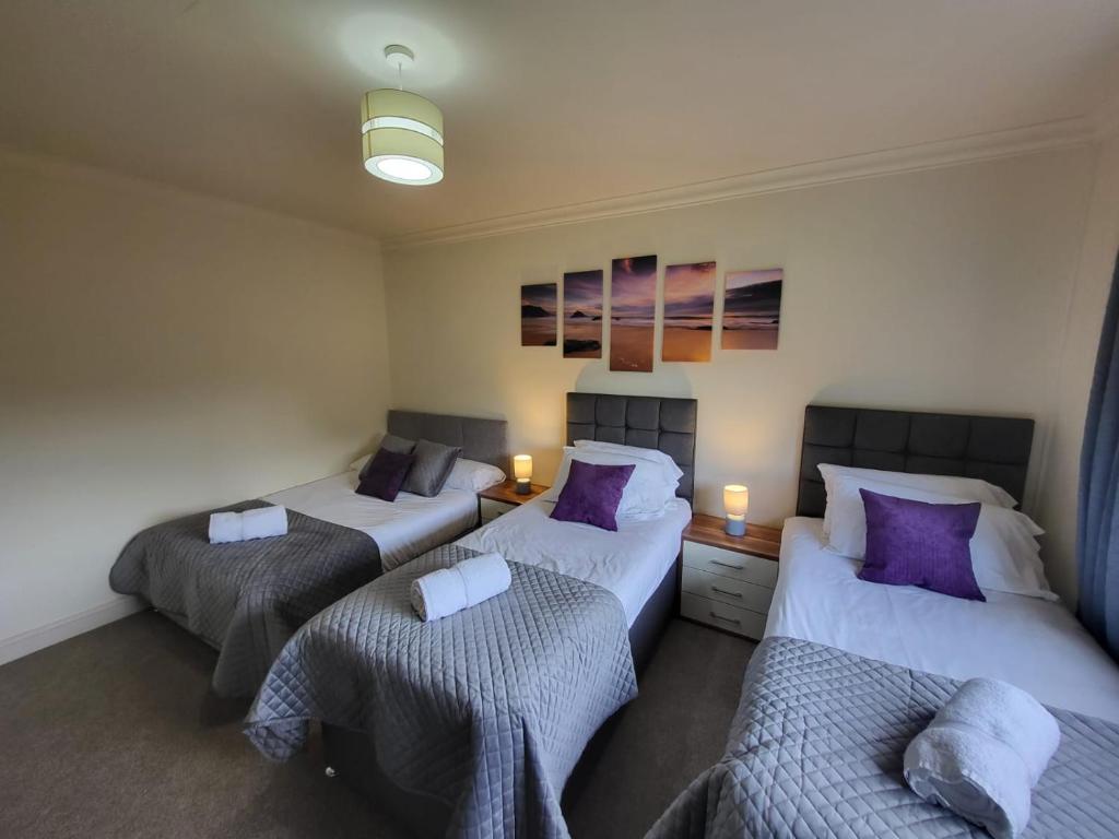 three beds in a room with purple pillows at Large 3 bed, great for contractors, with private parking in Provanmill