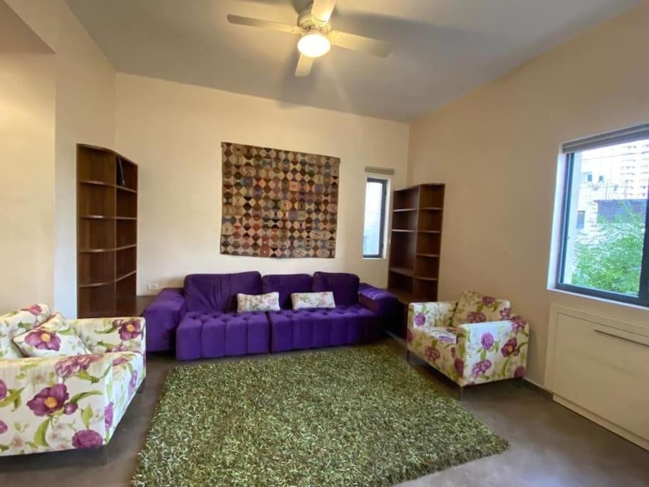 uma sala de estar com um sofá roxo e duas cadeiras em Golden key em Jerusalém