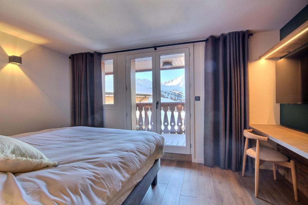 sypialnia z łóżkiem i biurkiem oraz balkon w obiekcie Chalet Topaz - 18 Couchages Sur les Pistes avec Services w mieście Plagne Villages