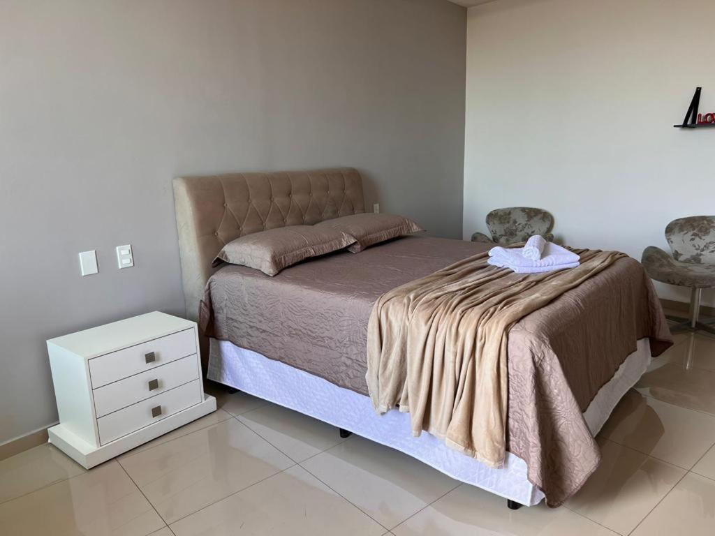 ein Schlafzimmer mit einem Bett mit einer Decke und einem Nachttisch in der Unterkunft Triplex independente in Cabo Frio