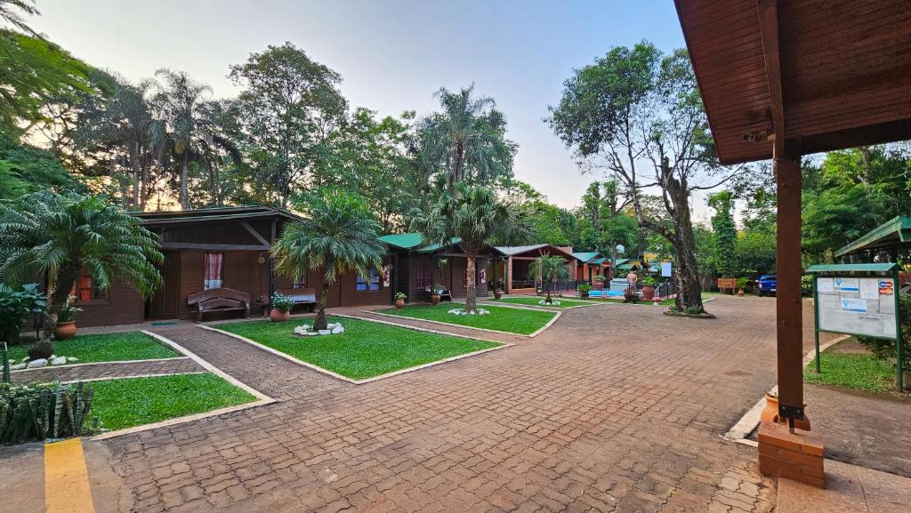a park with trees and a building with a brick driveway at Cabañas Rincon Santa Maria in Puerto Iguazú