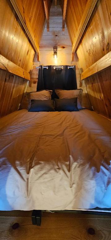 uma cama grande num quarto com tecto em madeira em Tiny House Ardennes em Fromelennes