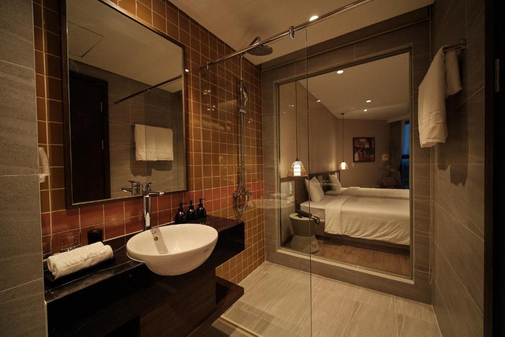 een badkamer met een wastafel, een spiegel en een bed bij Apec Mandala Chambay Mui Ne Ocean view in Ấp Thiẹn Ái