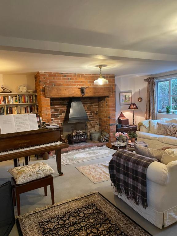 a living room with a piano and a fireplace at Joyce’s Barn 