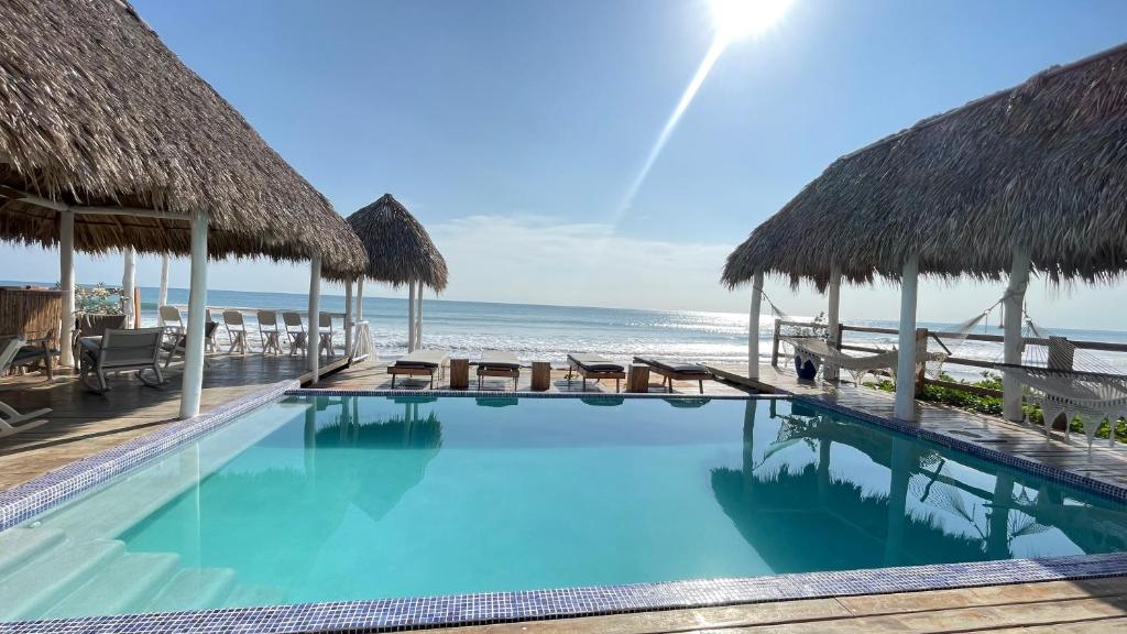 - une piscine sur la plage avec des parasols en chaume dans l'établissement AZVLIK, à Rivas