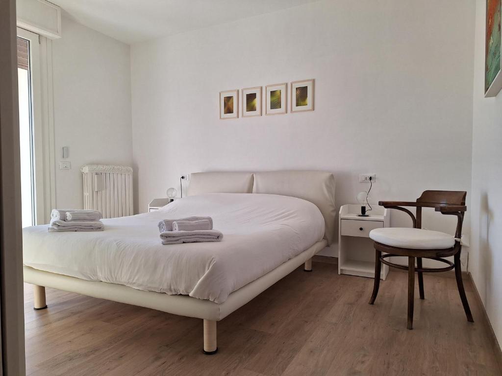 a white bedroom with a bed and a chair at casanita in Abano Terme