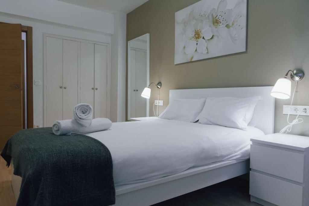 a bedroom with a large white bed with a green blanket at Apartamento familiar reformado en Amara, Estadio Anoeta, Donostia-San Sebastián in San Sebastián