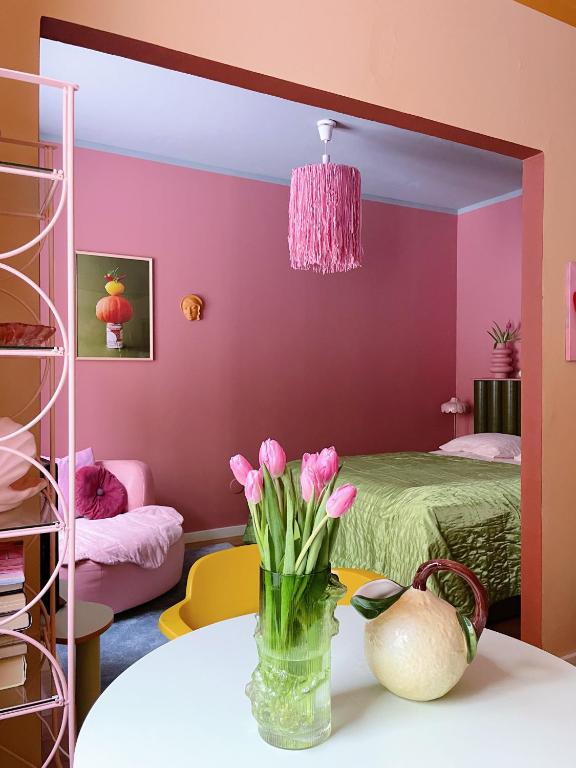 ヘルシンキにあるVärikäs koti lähellä keskustaaのピンクの花瓶がテーブルに飾られた部屋