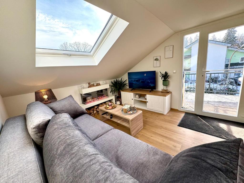 uma sala de estar com um sofá cinzento e uma grande janela em Schwarzwaldliebe Ferienwohnung mit eigenem Garten em Gaggenau