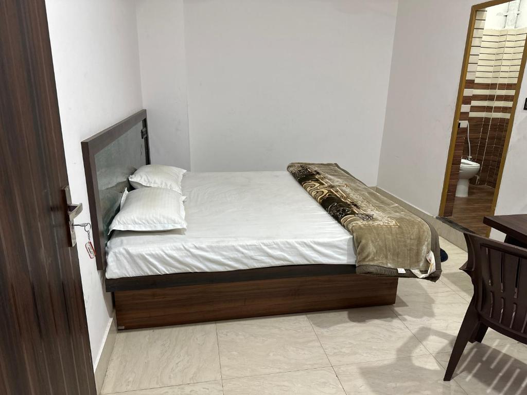 a bed with white sheets and pillows in a room at Hotel Sharda Palace in Deoghar
