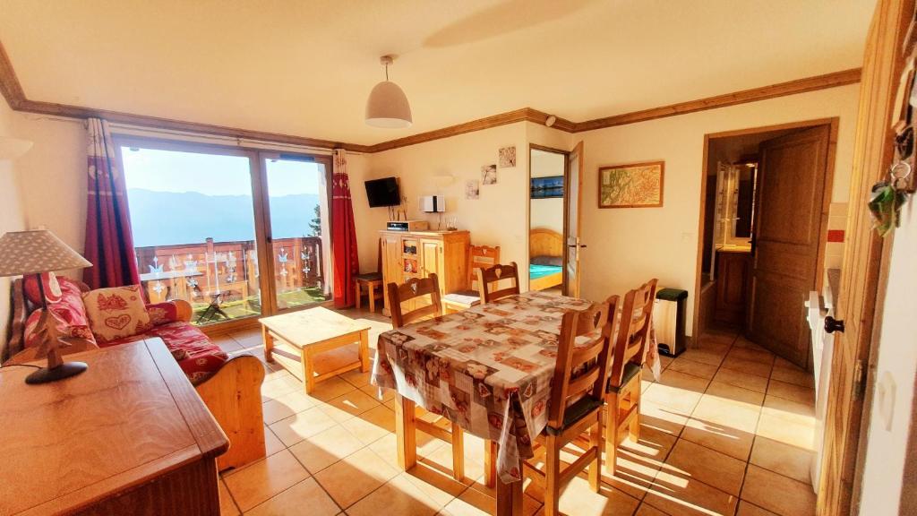 a dining room with a table and chairs and a window at les 7 laux immobilier chalet A in Prapoutel