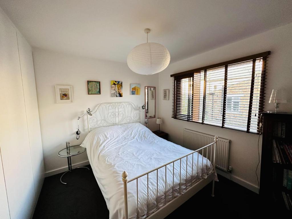 a bedroom with a white bed and a pendant light at Sunny Room in Highbury in London