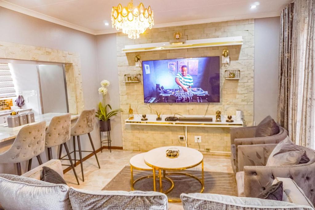 a living room with a tv on a brick wall at Homes of Ace 3 bedroom Villa in Pretoria